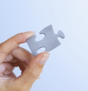 Puzzle Piece Between Woman's Fingers values - represented by hand holding piece of jigsaw puzzle