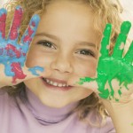 Smiling Girl with Hands Covered in Paint Be More Creative - shown by young girl with paint all over her hands